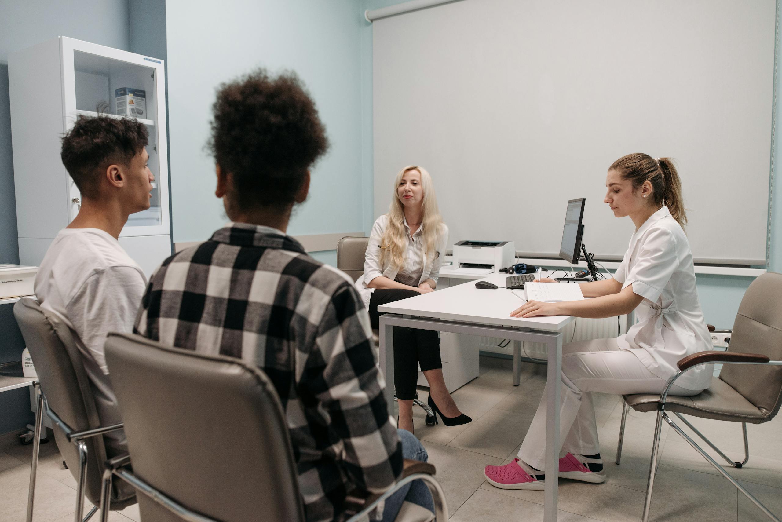 Doctors talking with patients during a medical appointment in a clinic office setting.